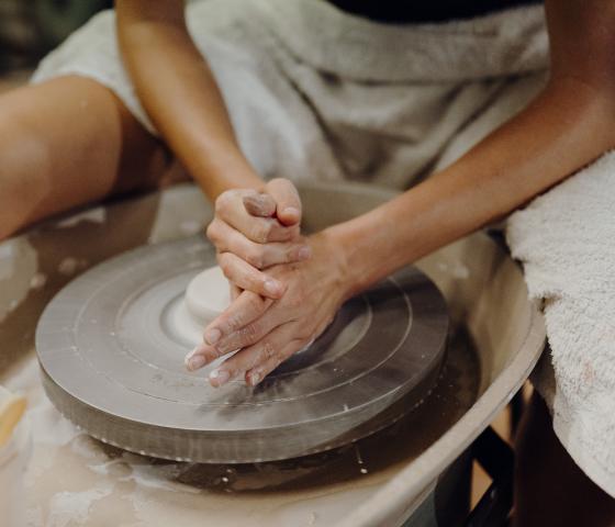 Student creating artwork on a pottery wheel