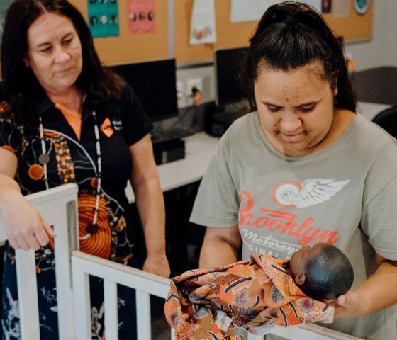 staff and students holding a doll 